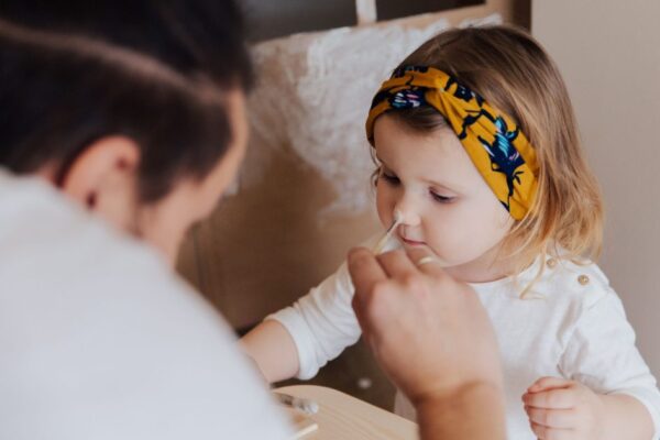 Father tenderly painting his young daughter's face during an art activity indoors.