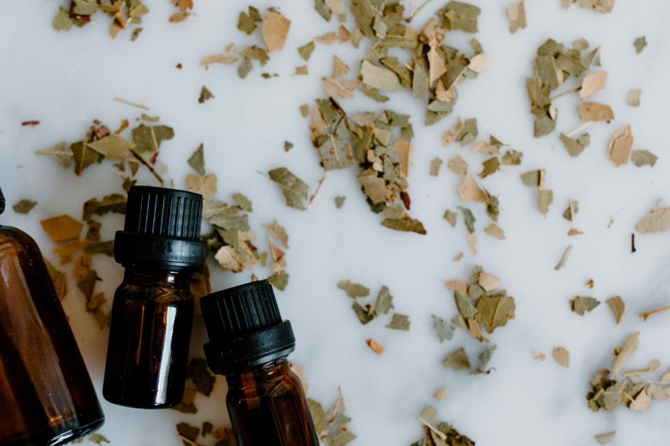 Infografis 38 Obat Bahan Alam Ilegal: Panduan Lengkap 2025 1 A flat lay of essential oil bottles with scattered dried herbal leaves on a white background.
