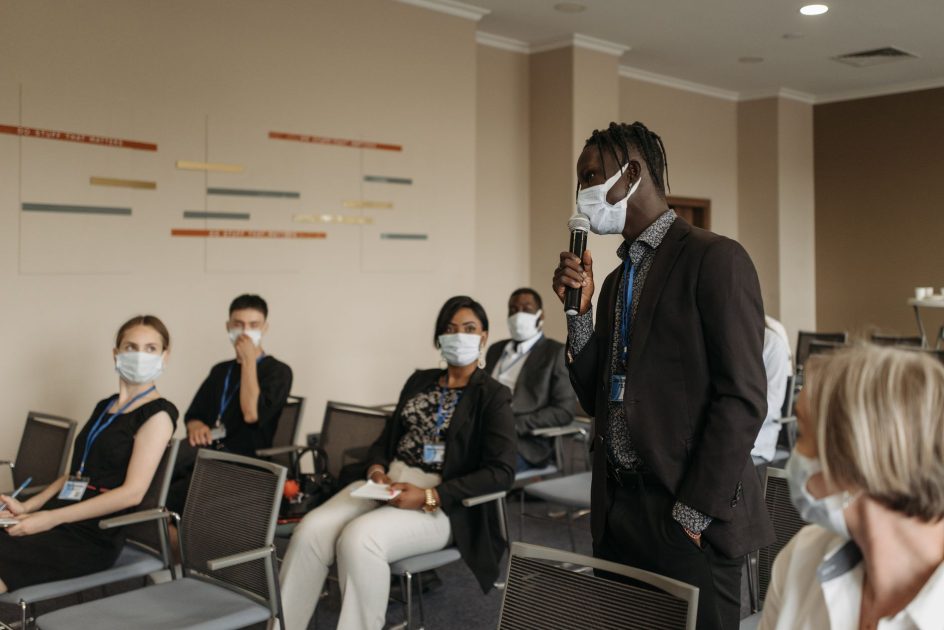 Infografis 6 Kandidat Pengganti Dirjen WHO: Panduan Lengkap 2025 1 Business seminar with participants wearing face masks, actively engaging in a discussion.