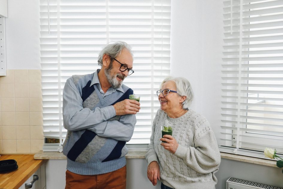 7 Cara Tiru Umur Panjang Jepang: Panduan Lengkap Anti-Stres 1 Senior couple smiling and enjoying green smoothies in a cozy kitchen setting.