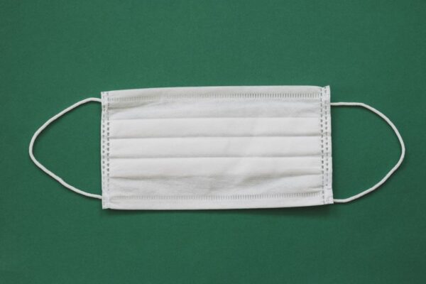 White surgical mask placed against a vibrant green background for health safety themes.