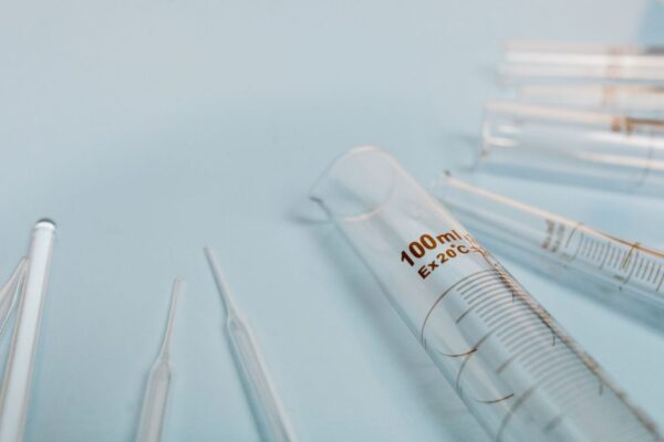 A collection of transparent glass test tubes on a soft blue surface, ideal for scientific research visuals.