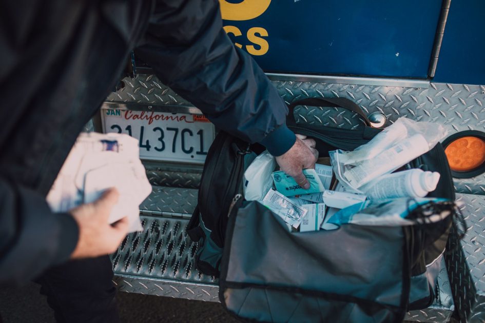 Pemprov Papua Tengah Bantu Alkes: 7 Panduan Lengkap 2025 1 A first responder accessing medical supplies from a bag beside an emergency vehicle.