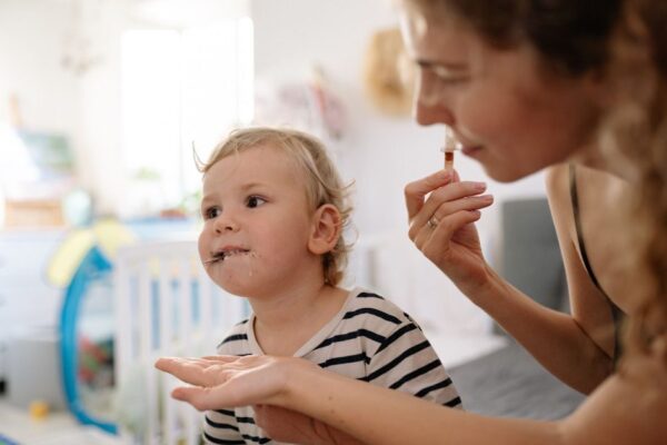 A mother and young child enjoying ice cream together indoors, sharing a special moment.