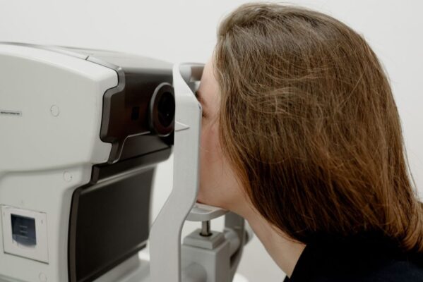 Side view of female client checking vision during medical treatment in ophthalmology clinic