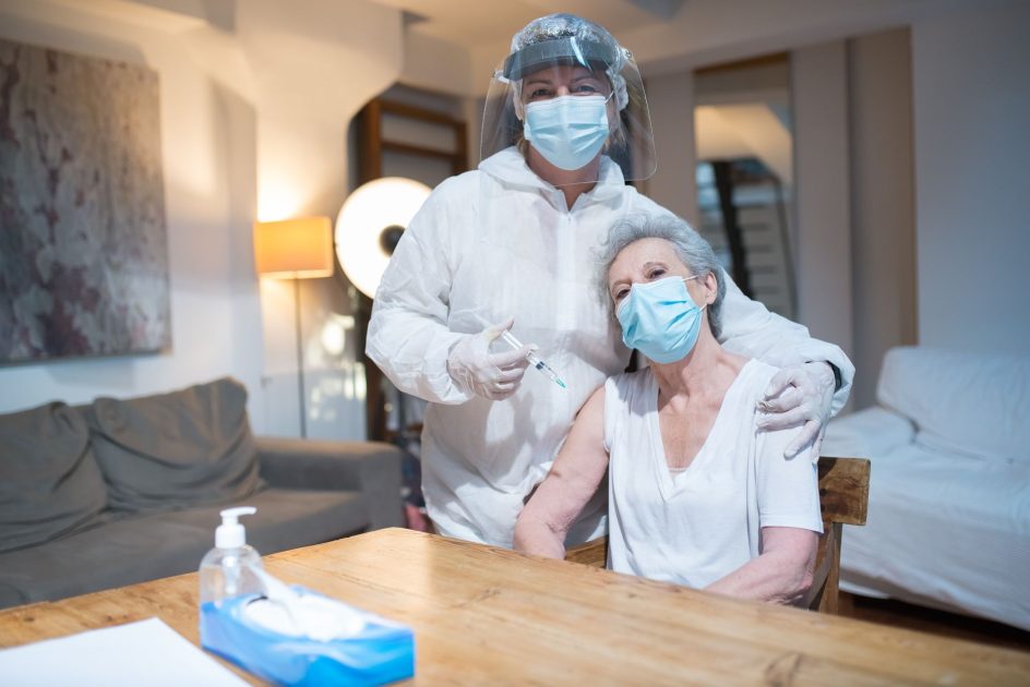 Respons Wamenkes Soal Obgyn Diduga: 7 Langkah Perlindungan 1 A healthcare worker in protective gear gives a vaccine to a senior woman at home.