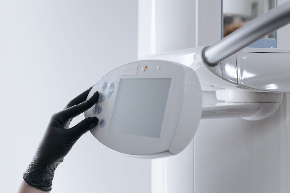 RSUD Masohi Dikeluhkan Rontgen Rusak: 9 Solusi Alat Medis 1 Close-up of gloved hand operating dental x-ray machine in clinical setting.