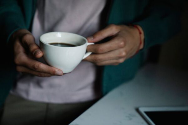 Close-up of hands holding a warm cup of coffee indoors, creating a cozy atmosphere.