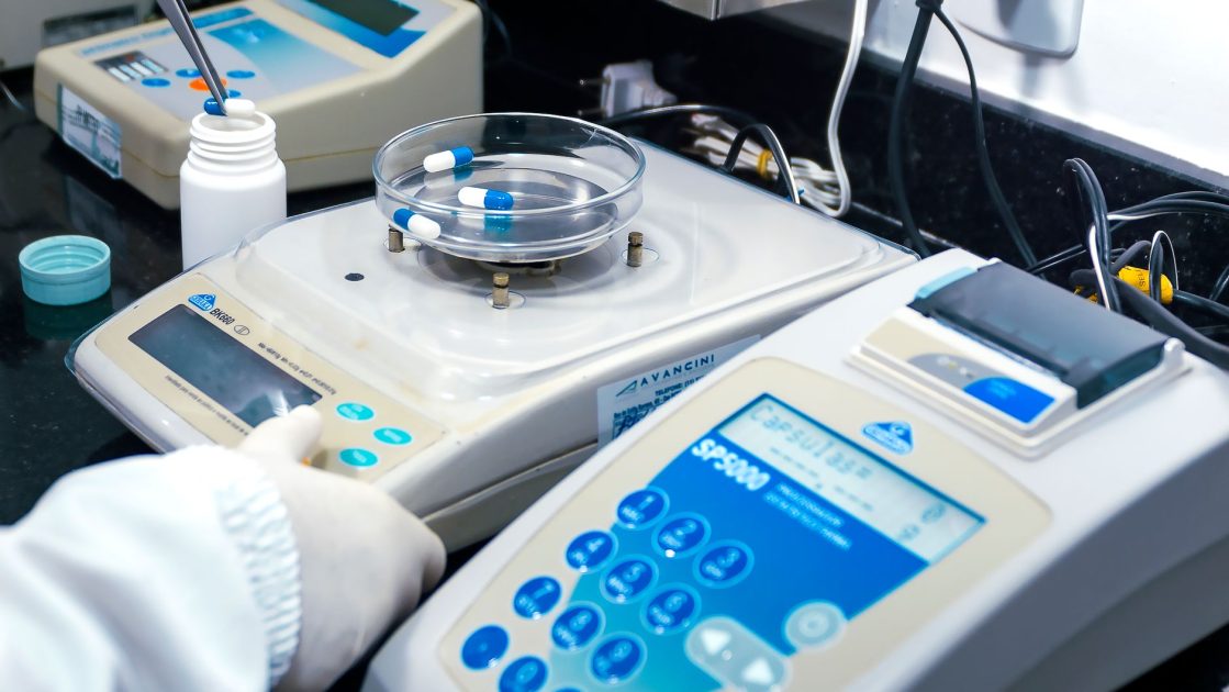 Setup Lab Farmasi Standar Kemenkes 2024: Checklist Lengkap 1 Close-up of laboratory equipment with capsules, capturing pharmaceutical analysis.