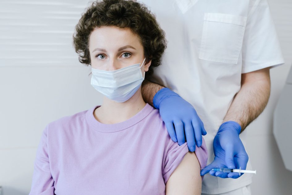 Tak Semua Kasus Influenza Butuh Obat: Panduan Lengkap 2024 1 A healthcare worker gives a vaccine injection to a masked patient, wearing gloves.