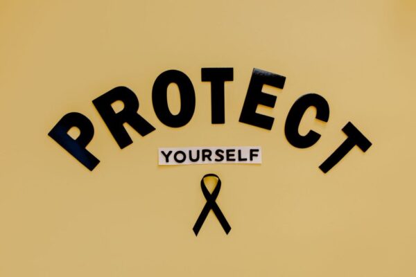 Conceptual awareness image with "Protect Yourself" text and black ribbon on yellow background.
