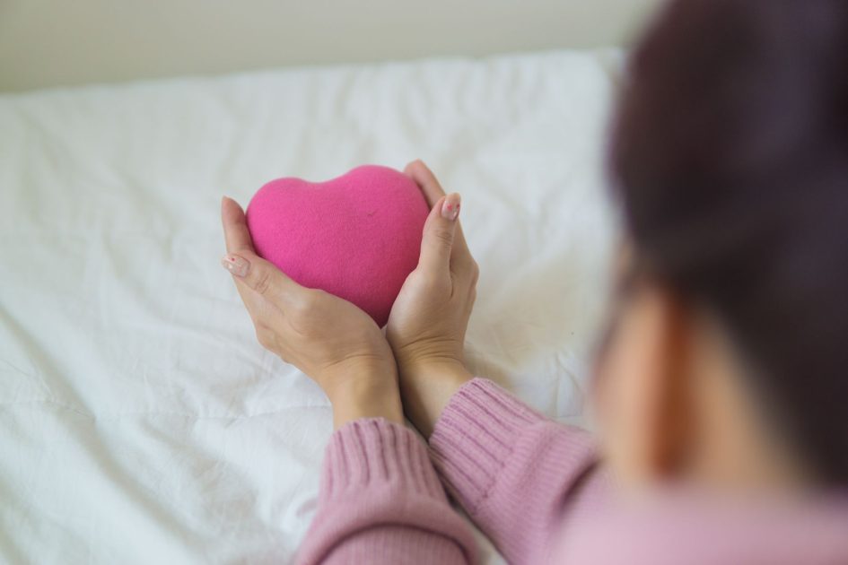 5 Hal Sebaiknya Dihindari Pagi: Panduan Jantung Sehat Anda 1 From above of unrecognizable female in sweater sitting on white blanket with pink heart shaped exercise ball in light room