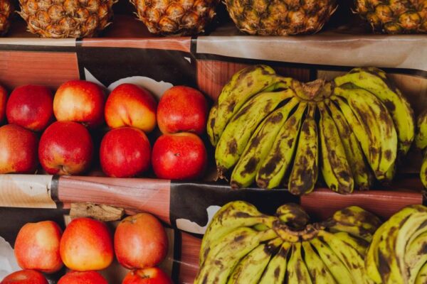A vibrant display of apples, bananas, and pineapples at a market. Ideal for food and lifestyle themes.