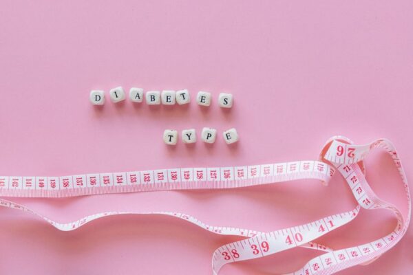Close-up of diabetes type block letters and measuring tape on pink background.
