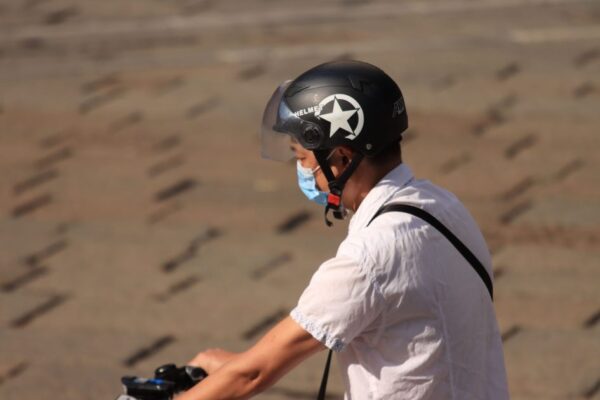 Side view of a man biking outdoors wearing a helmet and face mask for protection.