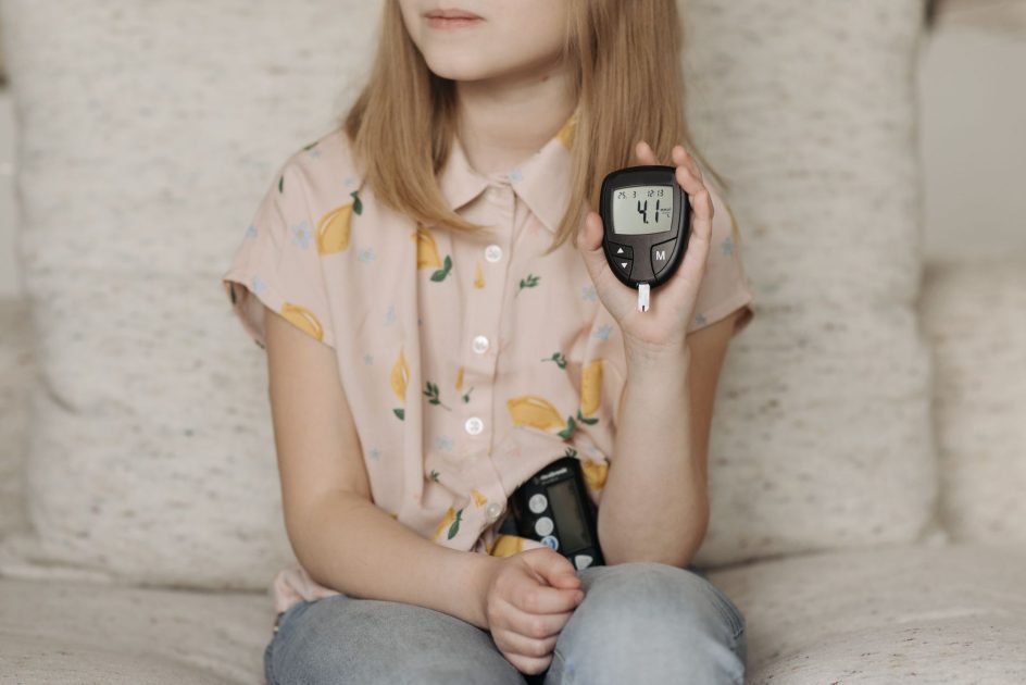 Intip Keseruan Morinaga Dunia Generasi: 7 Panduan Lengkap 1 A young girl sitting at home using a glucometer to monitor her blood sugar levels, illustrating diabetes management.