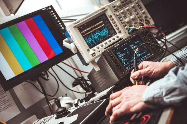 Technician operating laboratory electronic testing and measurement devices with colorful display.
