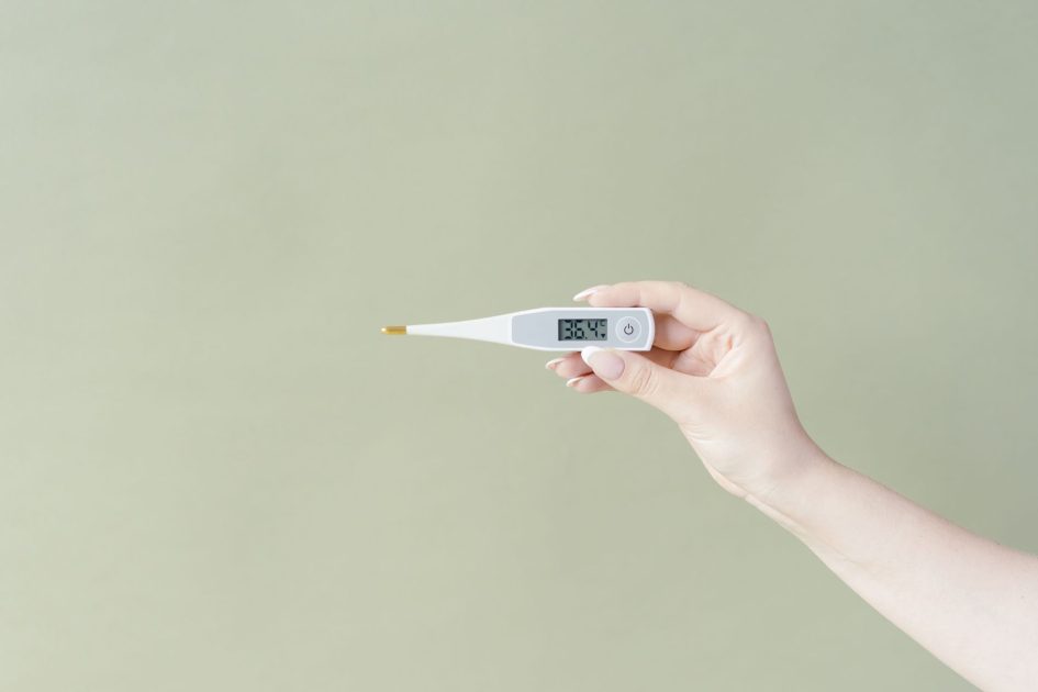 Kasus Flu Singapura Tertinggi Sejak 2024: Panduan Lengkap Pencegahan 1 Hand holding a digital thermometer displaying 36.4°C on a light green background, minimalistic style.