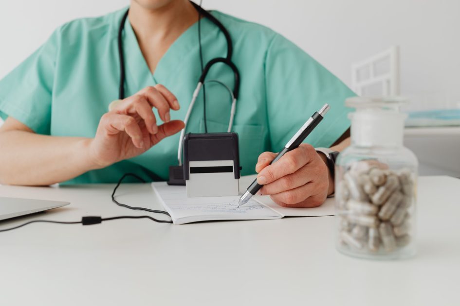 A medical professional writing a prescription in a clinical setting.