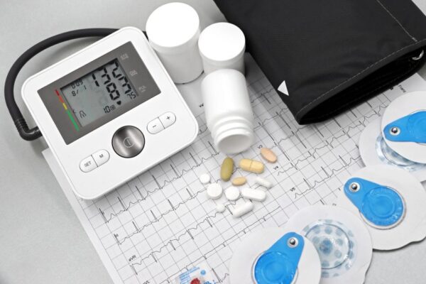 Flat lay of blood pressure monitor, pills, and ECG printout for heart health theme.