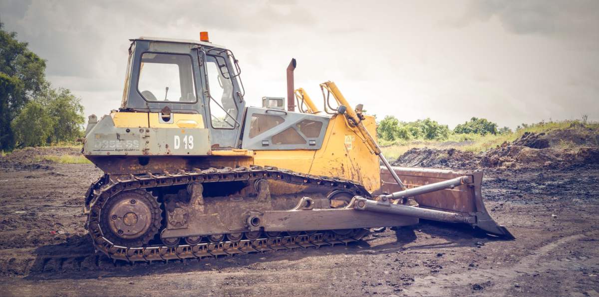 Pembangunan Tiga Gedung Baru RSUD: 9 Panduan Lengkap 2026 1 A powerful bulldozer on muddy construction ground under a cloudy sky.