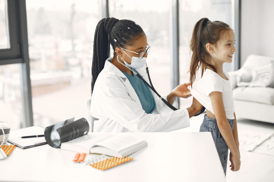 A female doctor gives a health check-up to a child in a bright clinic.
