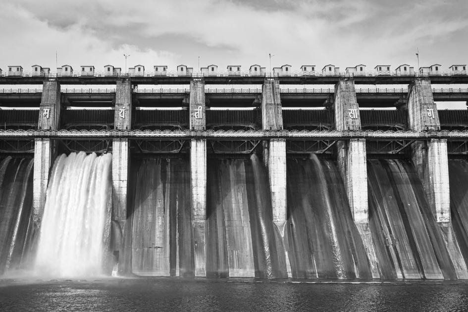 Sering Kebanyakan Minum Air Putih? 7 Risiko & Solusi Terbaik 1 Black-and-white photo of a concrete dam with water flowing through, showcasing architectural beauty.