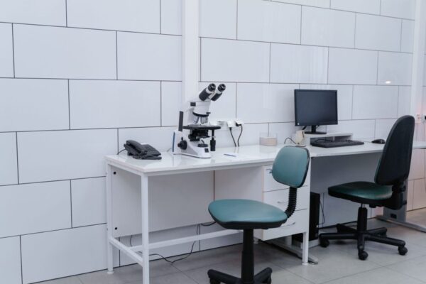 Modern laboratory with microscope, monitor, and office equipment on desk.