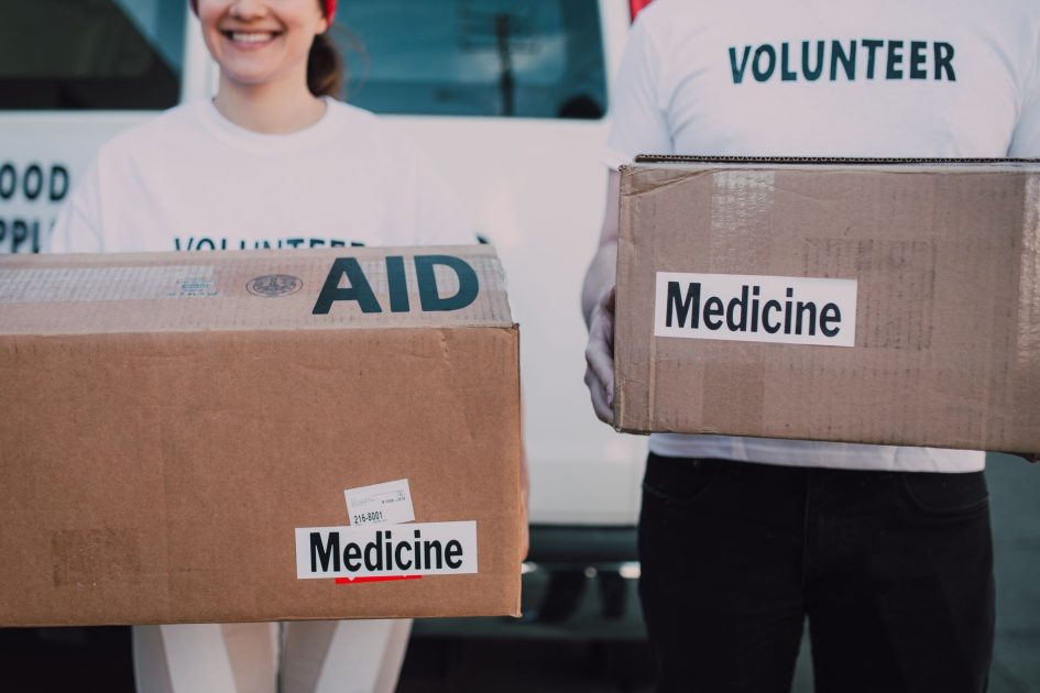 WHO Israel Blokir 60% Peralatan Medis: Panduan Lengkap 2025 1 Volunteers holding boxes labeled 'AID' and 'Medicine', preparing donations.